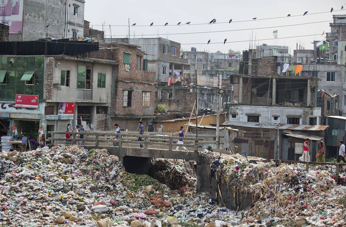 Masyarakat Bangladesh berjalan melintasi jembatan sungai Buriganga di Dhaka, yang penuh sesak oleh plastik dan sampah lainnya, 4 Juni 2018